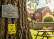 Tree in garden setting with a Tree Preservation Order plaque attached and a sticker below saying council approved.